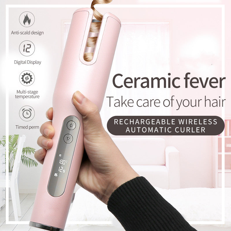 Pink hair curler with digital display held by a hand, against a blurred indoor background.