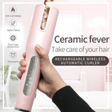 Pink hair curler with digital display held by a hand, against a blurred indoor background.