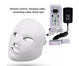 White LED face mask with remote control, charging cable, and power adapter on a white background