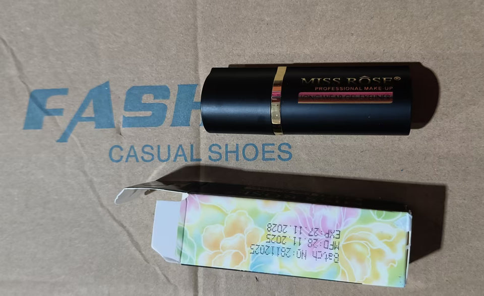 Black makeup compact with a floral tag on a beige surface, branded 'Mise En Scene'.