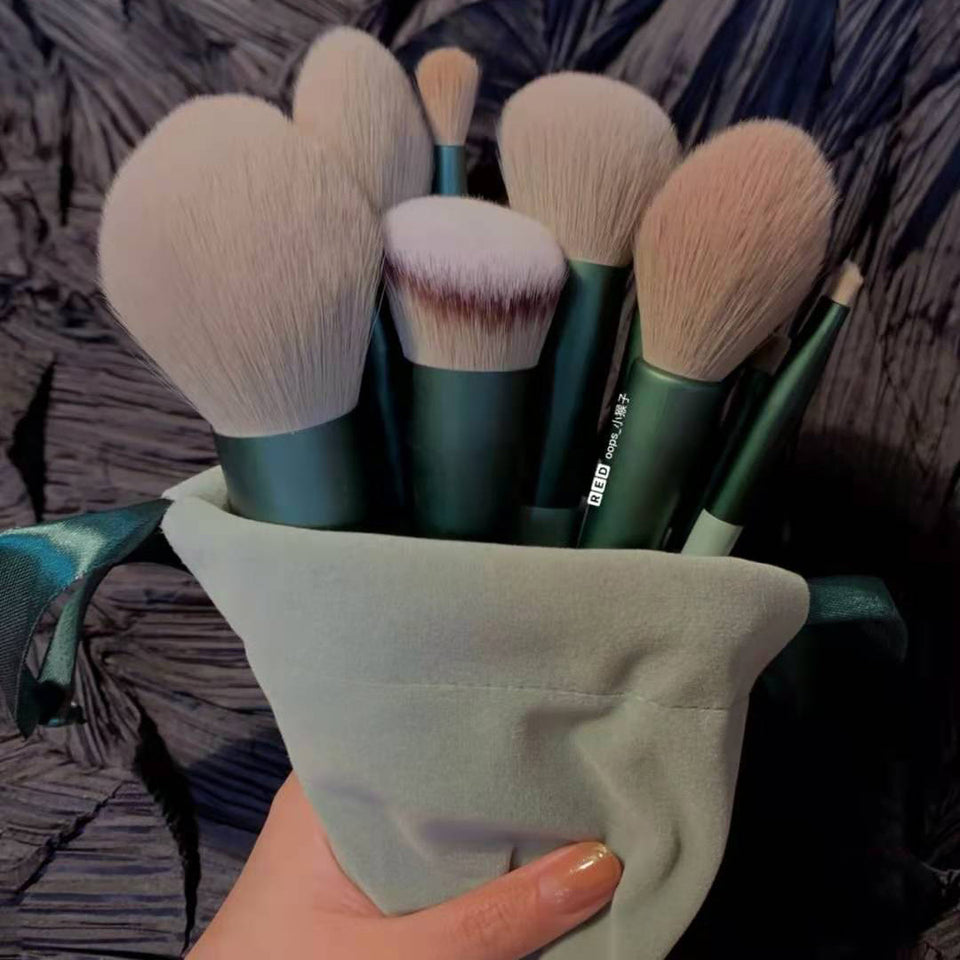 Set of makeup brushes in a green holder held by a hand against a textured background